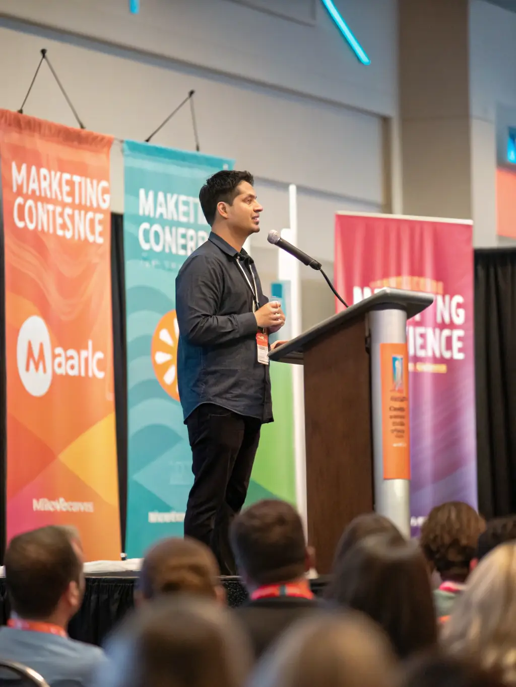 A professional headshot of a man with a beard, wearing a casual shirt, giving a keynote speech at an entrepreneurship conference.